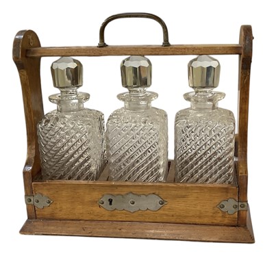 Lot 371 - An early 20th century oak tantalus with silver...