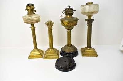 Lot 101 - Four brass column paraffin lamps and lamp...