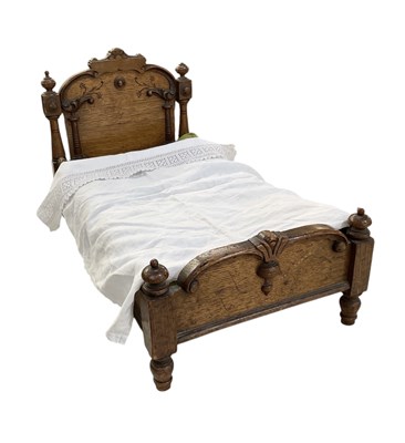 Lot 393 - An early 20th century oak doll's bed, with...