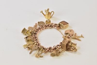 Lot 509 - A 9ct rose gold charm bracelet set with many...