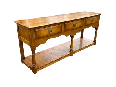 Lot 35 - A reproduction oak three drawer dresser base,...