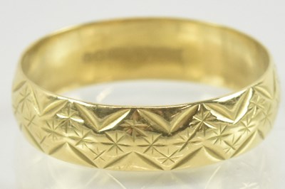 Lot 910 - An 18ct gold band ring with repeating pattern,...