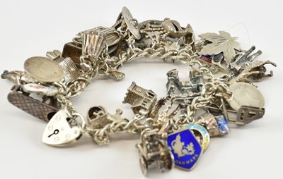 Lot 964 - A silver charm bracelet with thirty-four...