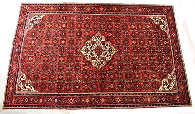 Lot 155 - A hand-knotted red ground rug, with central...