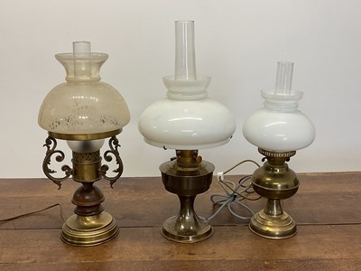 Lot 351 - Three brass oil lamps with glass shades and...