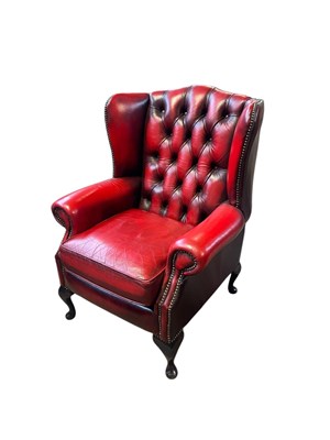 Lot 56 - A deep red leather Chesterfield type wing back...