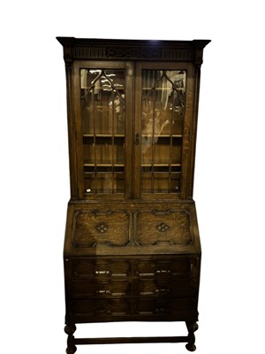 Lot 279 - A 1920s carved oak bureau bookcase, with...