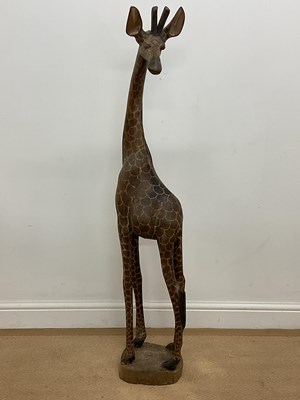 Lot 394 - A carved wooden model of a giraffe on a wooden...