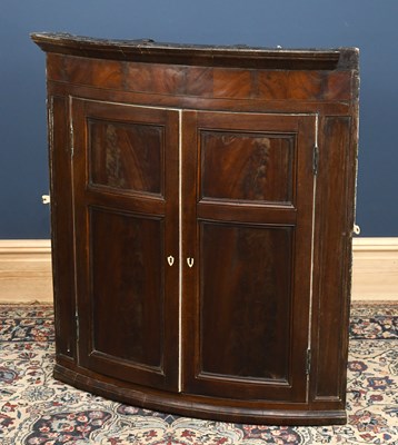 Lot 2825 - A George III mahogany bowfront corner cupboard,...