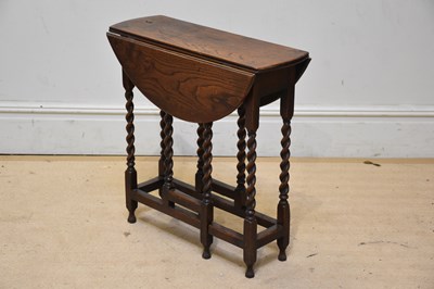 Lot 1061 - A small oak oval drop-leaf table on barley...