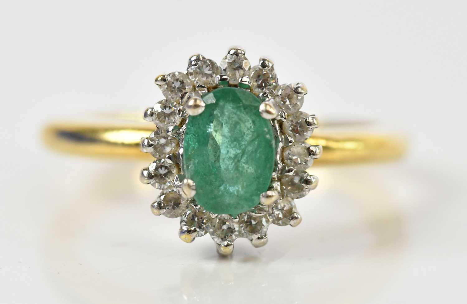 Lot 100 - An 18ct yellow gold diamond and emerald oval...