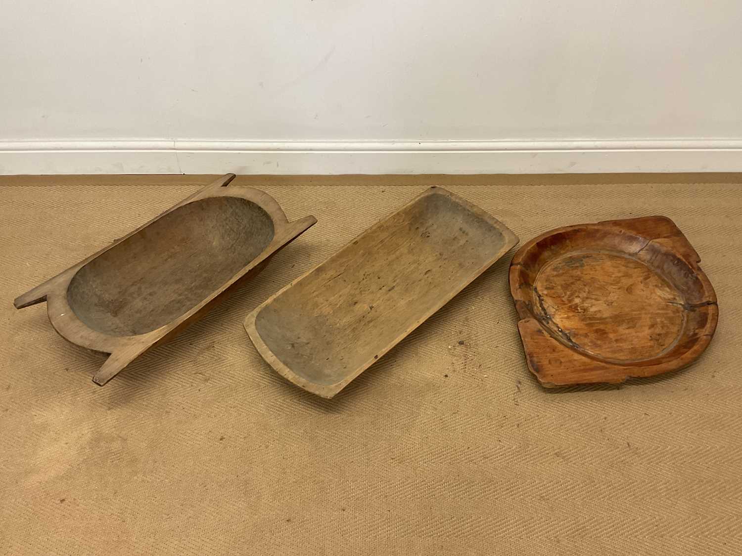 Lot 670 - Two carved wooden dough troughs and a carved...