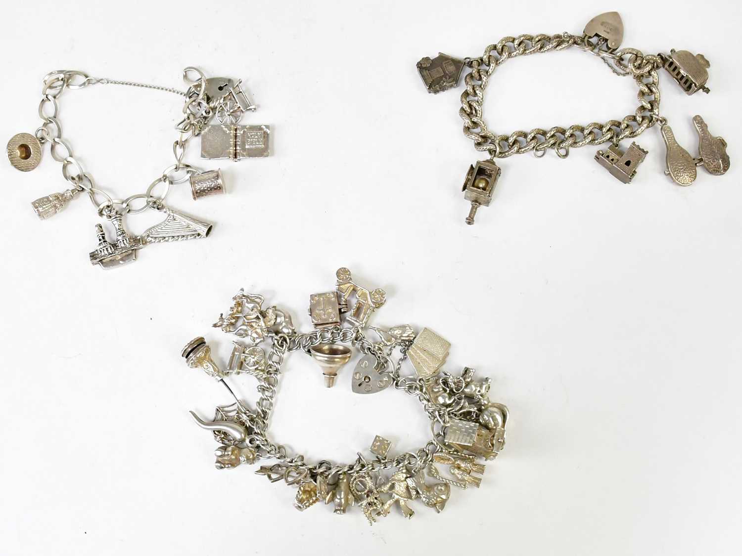 Lot 1053 - Three hallmarked silver charm bracelets set...