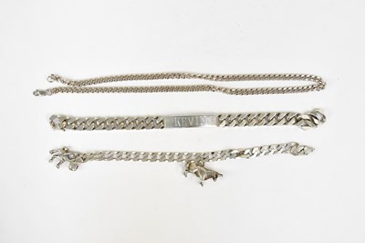 Lot 1425 - A silver curb link bracelet with two charms,...
