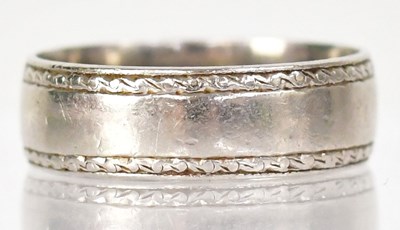 Lot 1254 - A platinum wedding band with engraved borders,...