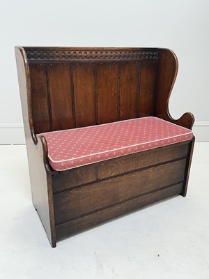 Lot 1071 - An oak wingback settle, with hinged seat,...
