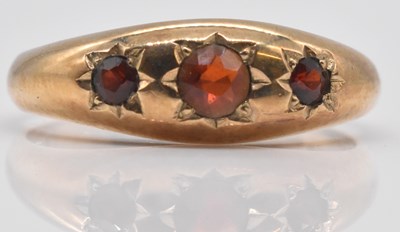 Lot 542 - A 9ct yellow gold three stone garnet set ring,...