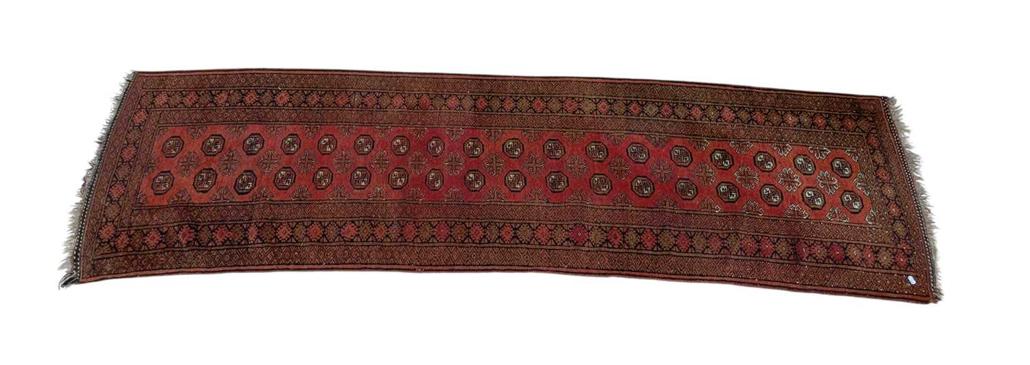 Lot 1301 - A Bokhara red ground wool runner, worked with...