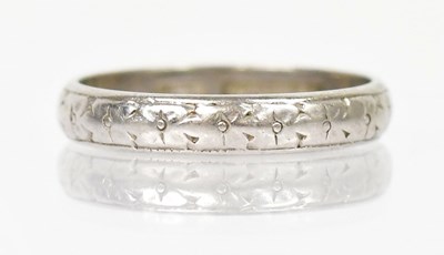 Lot 1255 - A platinum ring with engraved decoration of...