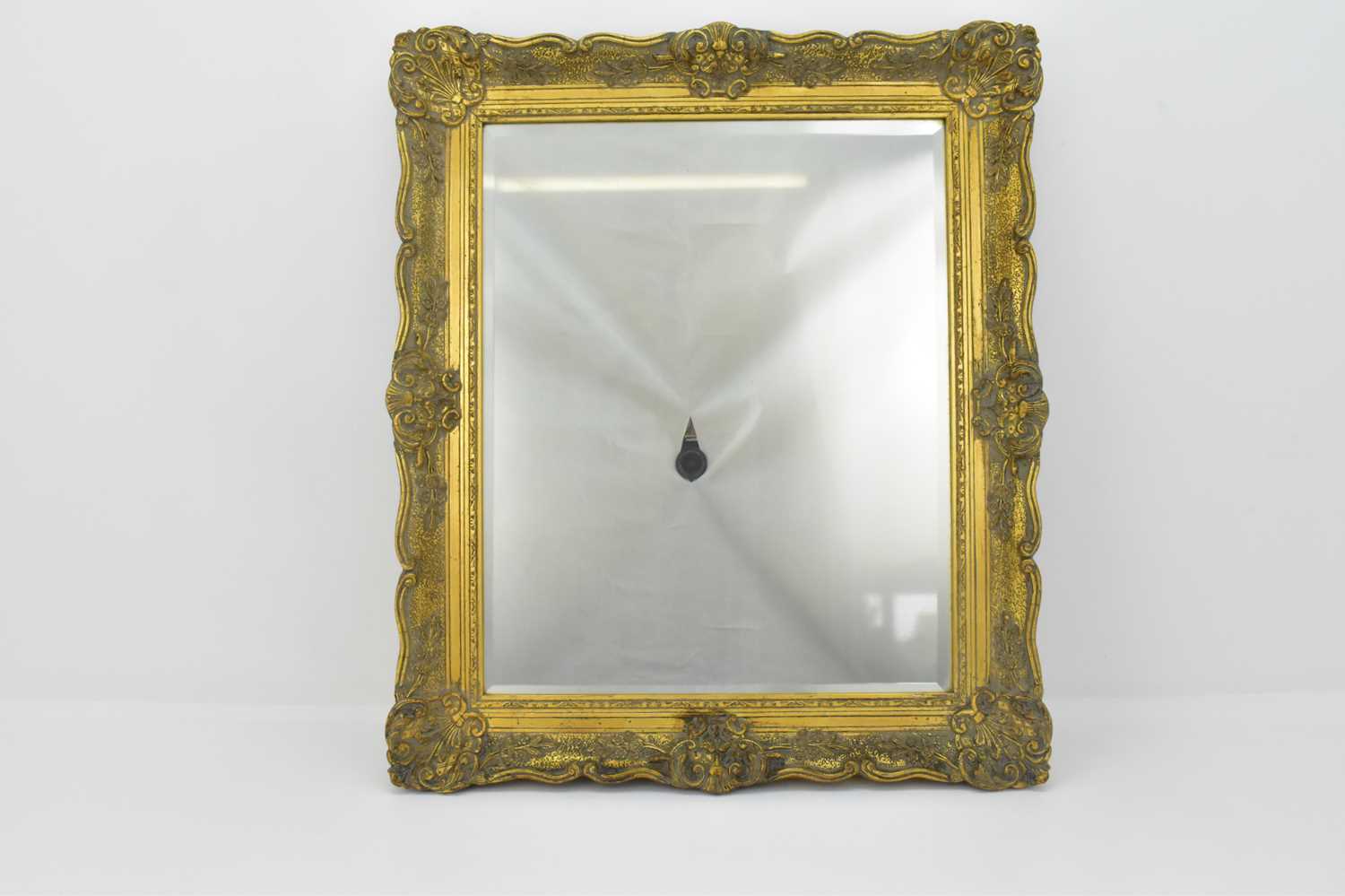 Lot 61 - A bevelled edge wall mirror in an ornate...
