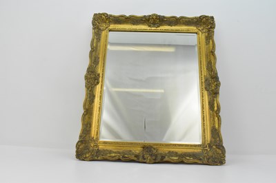 Lot 61 - A bevelled edge wall mirror in an ornate...