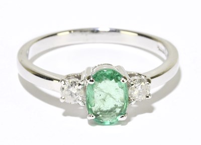 Lot 1215 - A 9ct white gold emerald and diamond three...