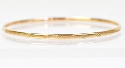 Lot 1414 - A 9ct yellow gold bangle with simple engraved...