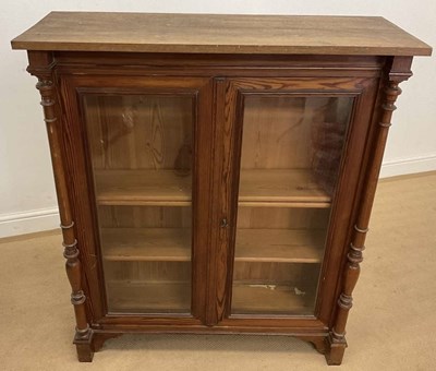 Lot 748 - A stained pine glazed cabinet, with turned...