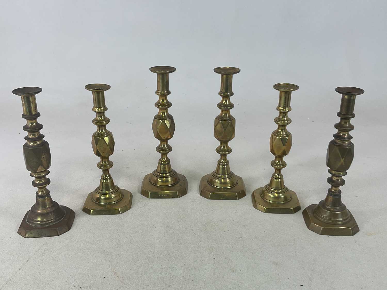 Lot 206 - Three pairs of brass candlesticks, the kings,...