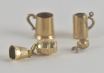 Lot 1203 - Four 9ct gold charms comprising a mug, thimble,...