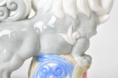 Lot 394 - YOSHIMI K; a pair of porcelain lion dogs,...