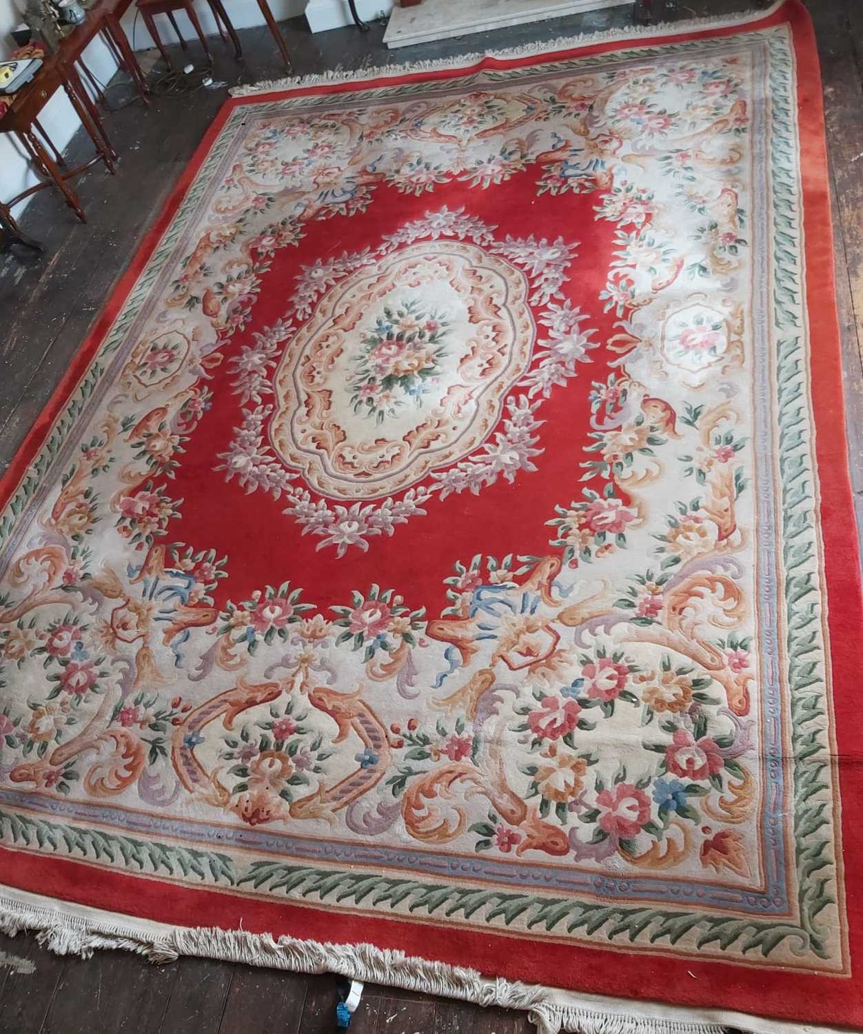 Lot 64 - A large Chinese wool carpet of red ground with...