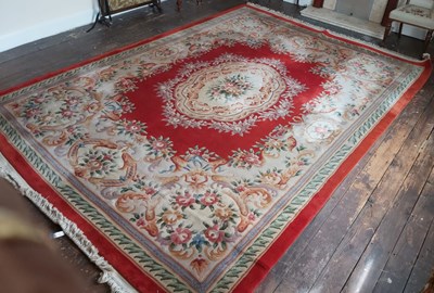 Lot 64 - A large Chinese wool carpet of red ground with...