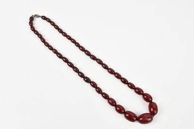 Lot 303 - A strand of cherry amber coloured beads,...