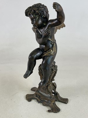Lot 317 - A bronzed brass cherub seated on a decorative...