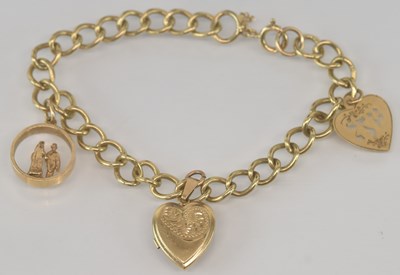 Lot 567 - A 9ct yellow gold charm bracelet, with three...