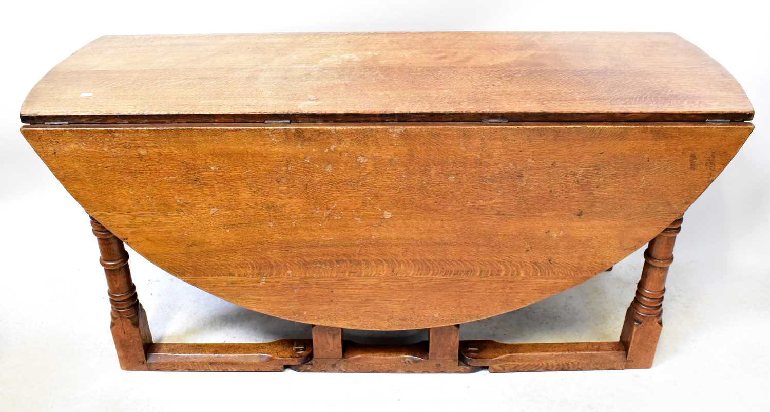 Lot 53 - A modern oak circular drop-leaf table raised...