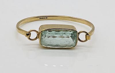 Lot 747 - A 9ct yellow gold bangle with large pale blue...