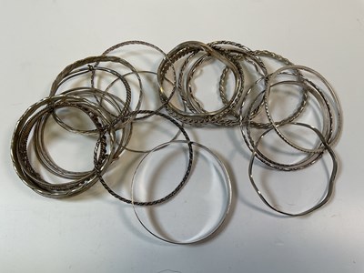 Lot 959 - Nineteen silver and white metal bangles, one...