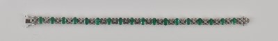 Lot 563 - An 18ct white gold diamond and emerald set...
