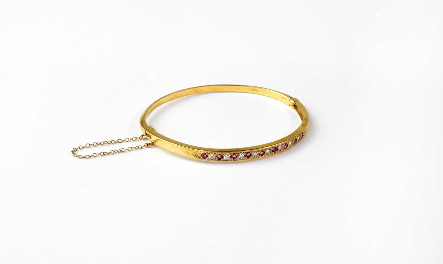 Lot 1122 - A 9ct gold bangle set with alternating rubies...