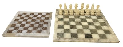 Lot 322 - An onyx chessboard, with half set of chess...