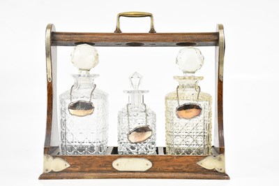Lot 340 - An early 20th century oak tantalus with silver...