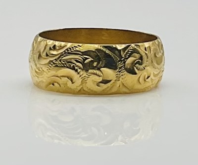 Lot 628 - An 18ct yellow gold engraved wedding band,...