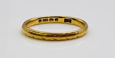 Lot 654 - A 22ct engraved yellow gold wedding band,...