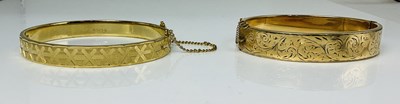 Lot 675 - Two rolled gold bangles and a yellow metal...