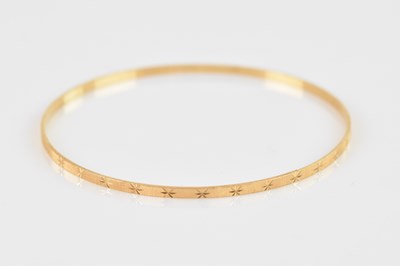 Lot 1186 - A yellow metal bangle, with engine turned and...