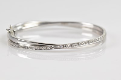 Lot 1162 - A white metal hinged bangle, stamped '375',...