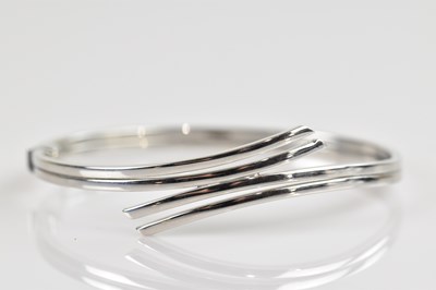 Lot 1213 - A white metal hinged snap bangle, stamped '375'...