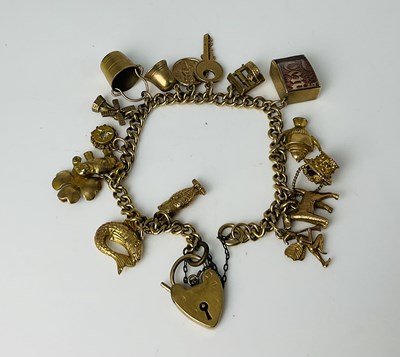 Lot 574 - A 9ct yellow gold charm bracelet, with sixteen...